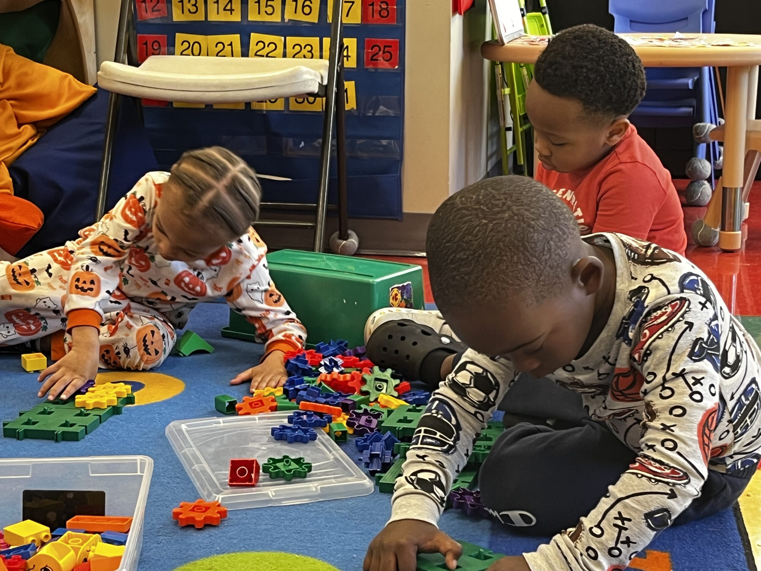 Toddler students playing with blocks on carpet.