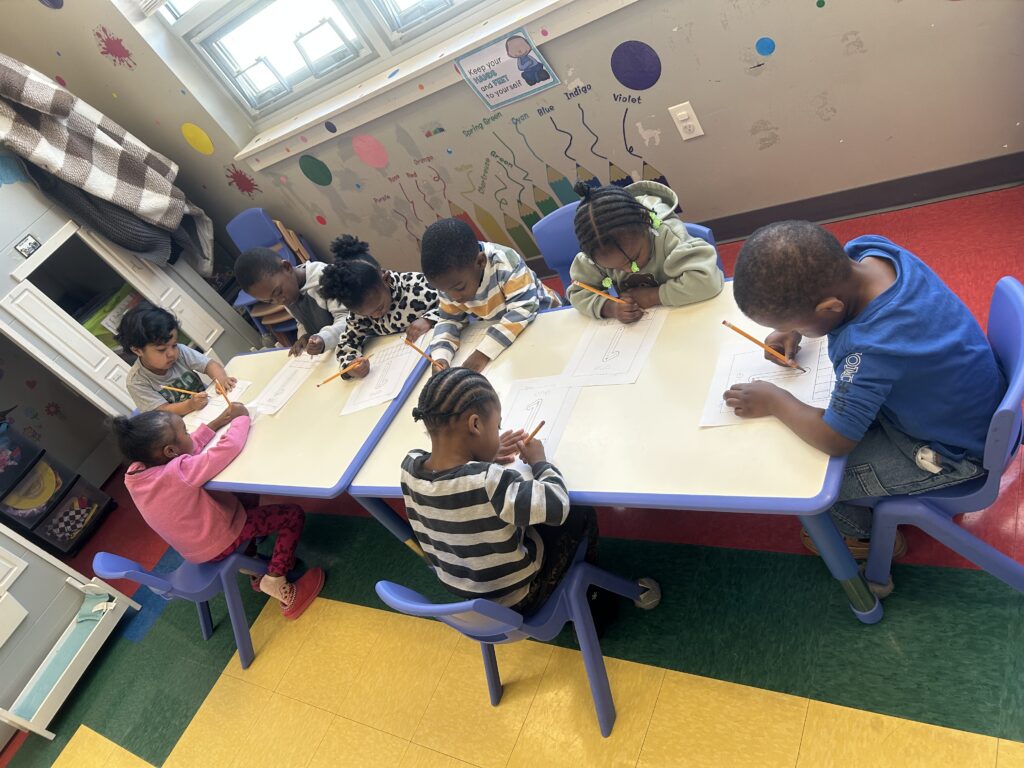 PreK-3 students at table practicing tracing skills.